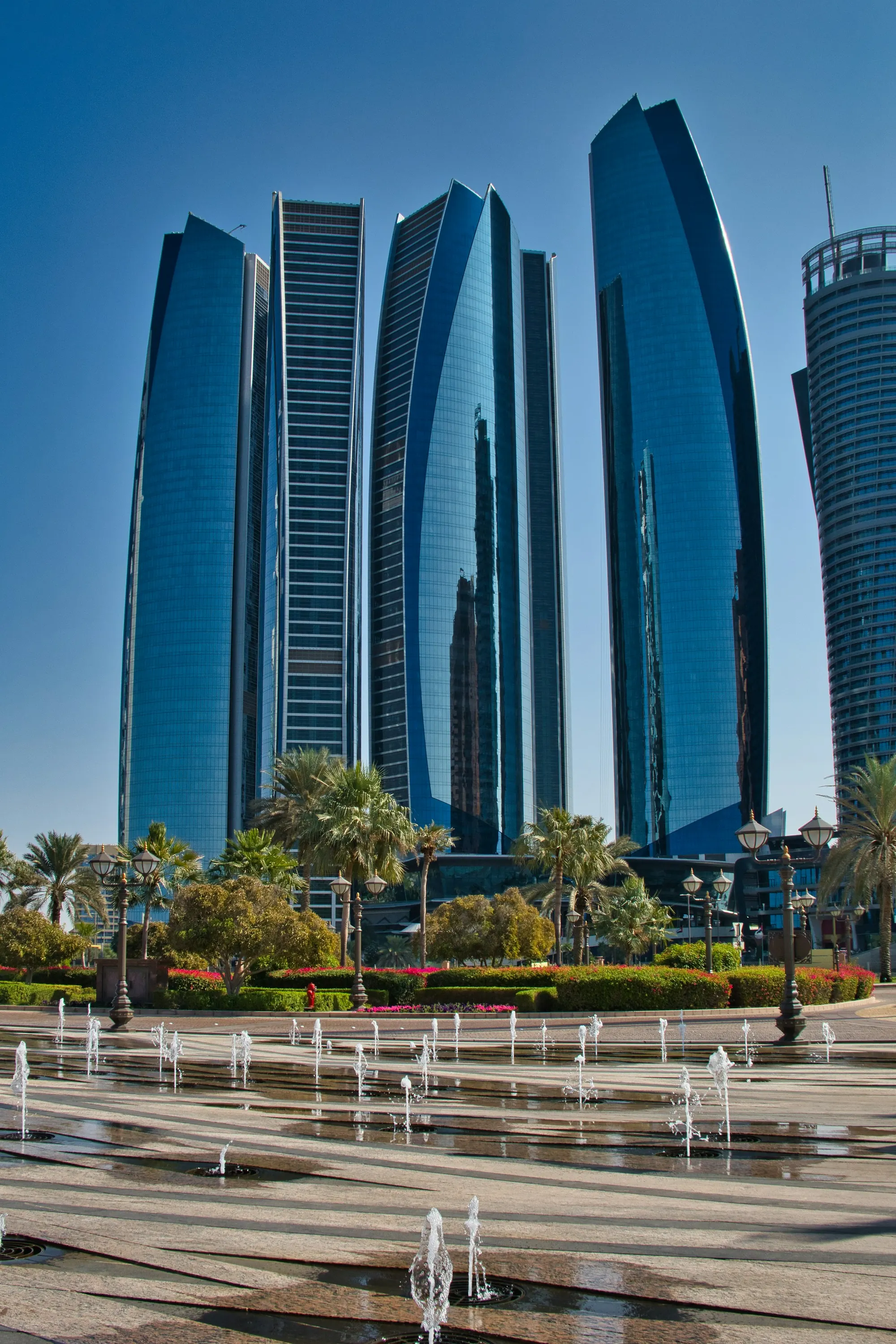 Glass towers above a plaza with fountains